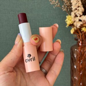 Main avec un stick à lévres rouge fruit des bois